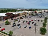 Exterior aerial view of multiple buildings and parking areas apart of Central Texas Marketplace